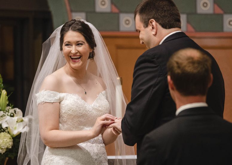 Bride putting ring on grooms finger at wedding ceremony