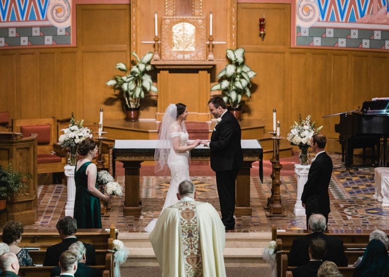 Bride putting ring on grooms finger at church wedding