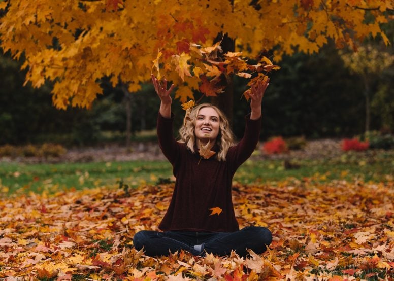 Happy young woman playing in leaves