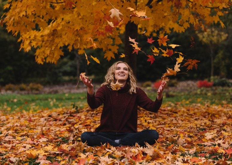 Happy young woman sitting in leaves