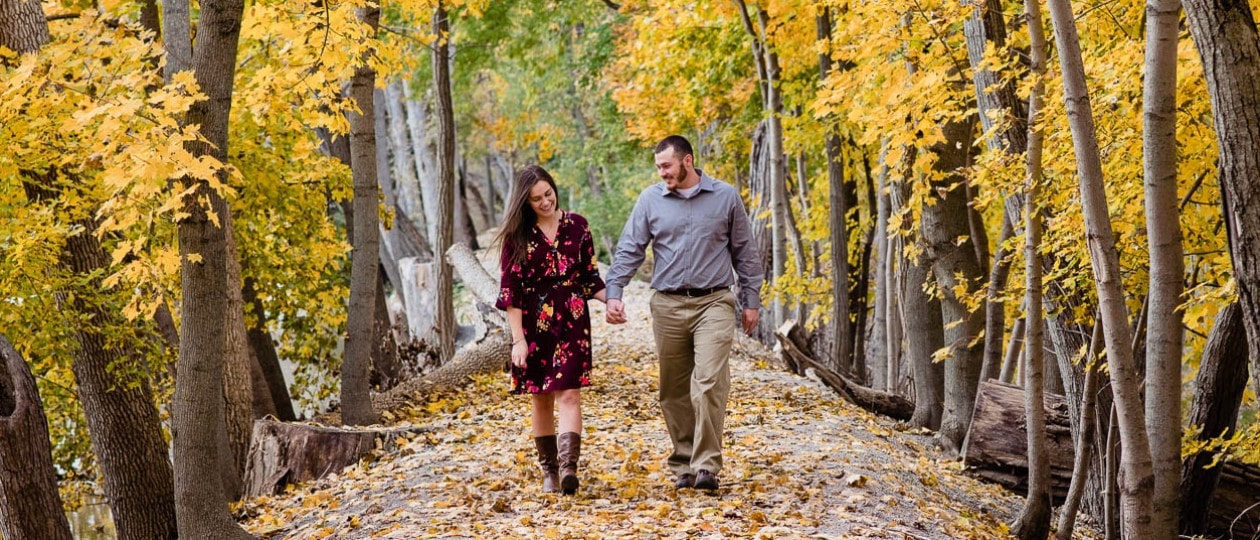 Fall engagement session with couple walking in leave covered path