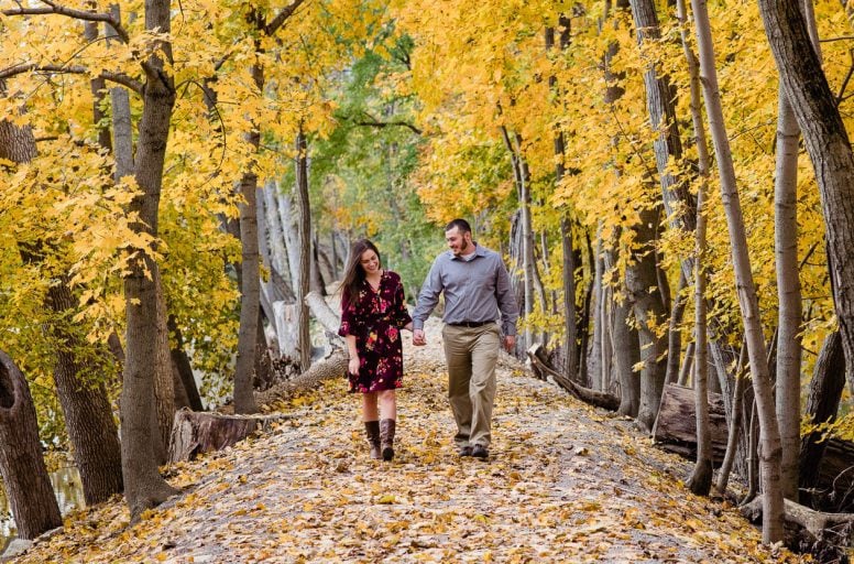 Fall engagement session with couple walking in leave covered path